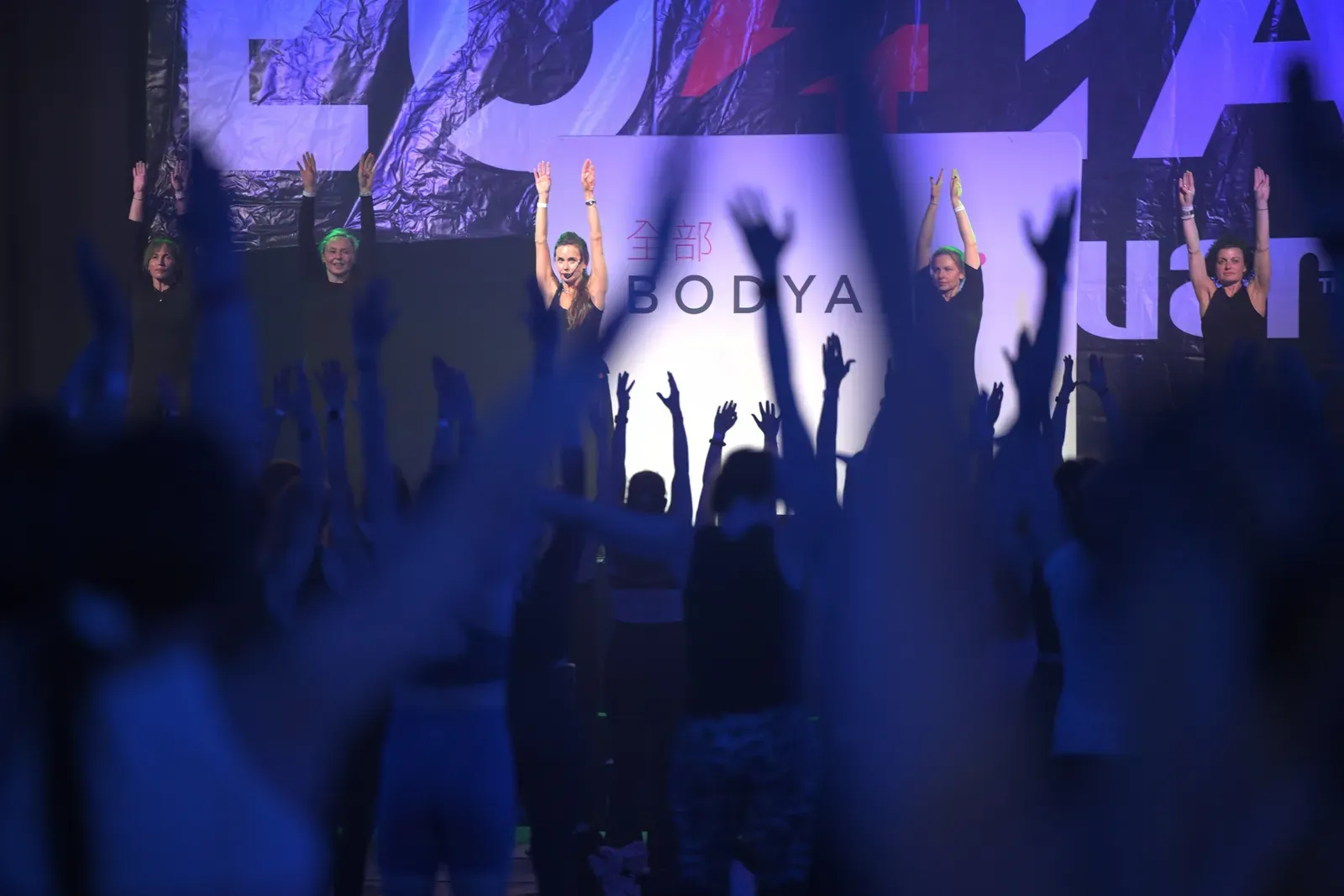 Full hall with hands raised during a group session